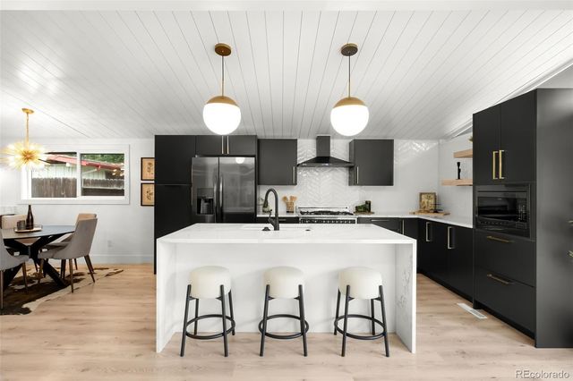 a kitchen with stainless steel appliances a dining table chairs and stove top oven