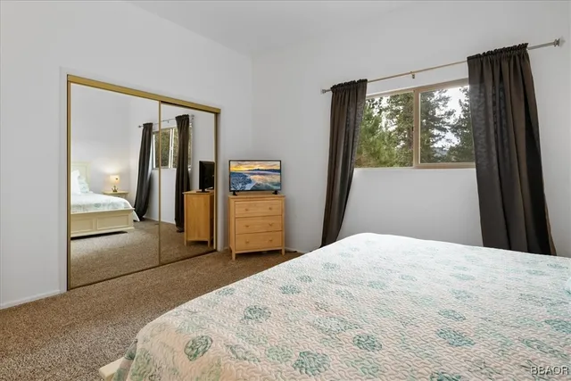 a bedroom with a large bed and a large mirror next to a window