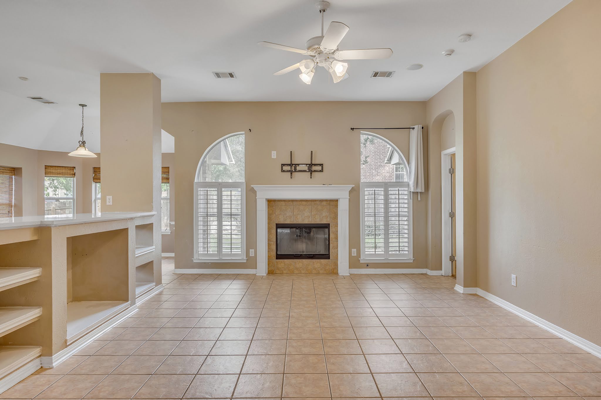 2726 Grimes Ranch Road Austin, TX 78732 - Photo 14 of 35 Unfurnished living room with a ceiling fan, light tile patterned floors, a fireplace, and built in features