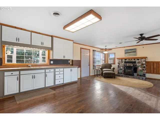 a view of an empty room with wooden floor and a fireplace