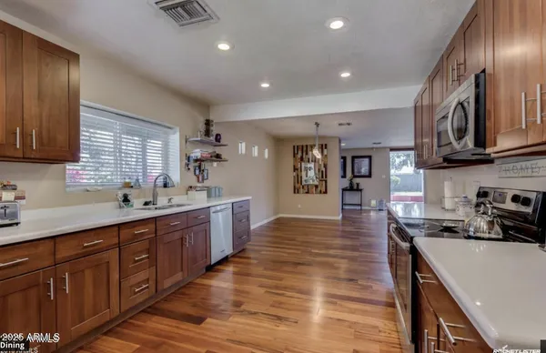 a large kitchen with stainless steel appliances granite countertop a lot of counter space and wooden floors