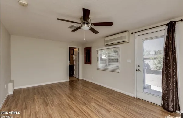 a view of empty room with wooden floor and fan