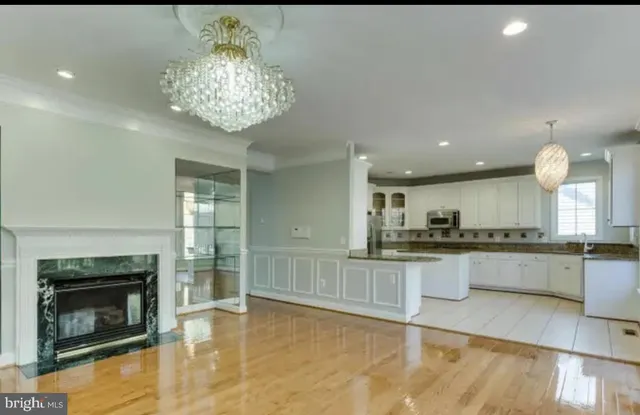 a kitchen with stainless steel appliances granite countertop a stove top oven a sink dishwasher and a fireplace with wooden floor