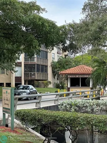 a front view of a building with lots of trees and plants
