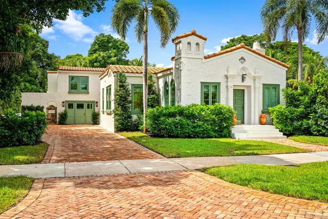 a view of white house with a yard and potted plants