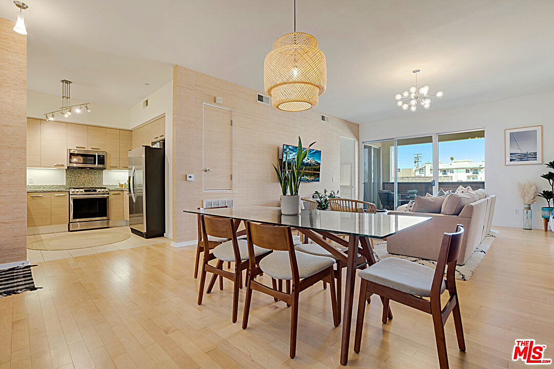 a dining room with wooden floor a chandelier a glass table and chairs