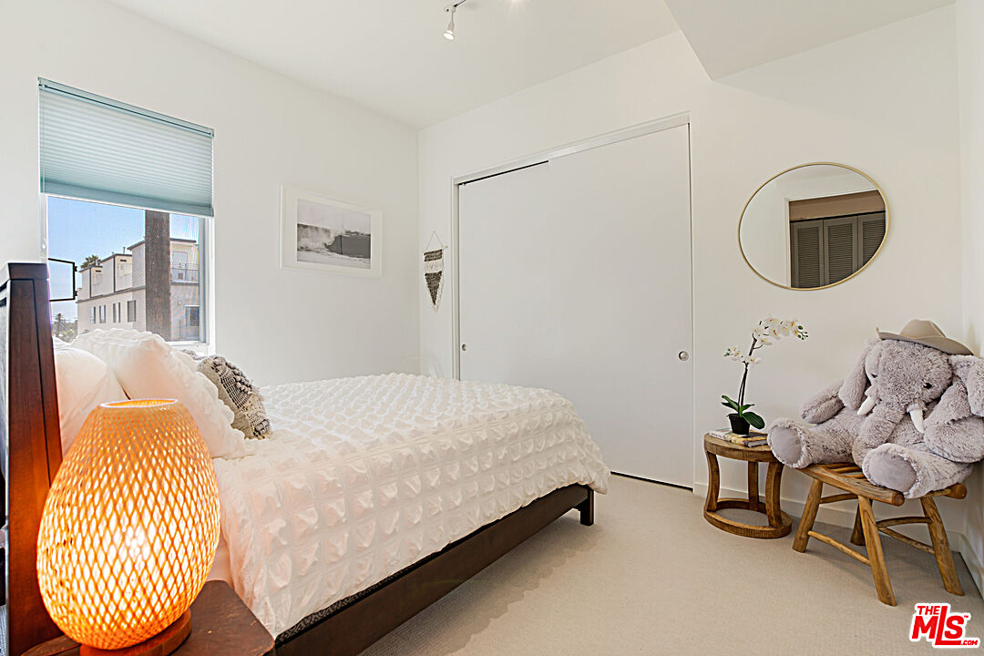 12411 Pacific Avenue, Unit 205 Los Angeles, CA 90066 - Photo 18 of 21 a bedroom with a bed a mirror and a window