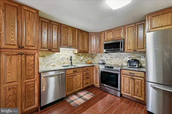 a kitchen with cabinets stainless steel appliances and wooden floor