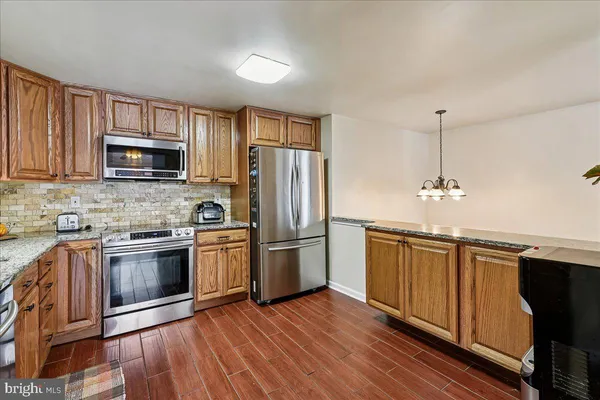 a kitchen with granite countertop wooden floors stainless steel appliances and a window