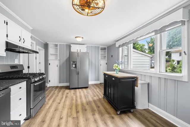 a kitchen with stainless steel appliances granite countertop a stove a refrigerator a sink and dishwasher with wooden floor