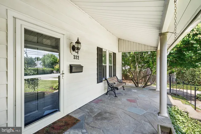 a porch with a bench next to a yard