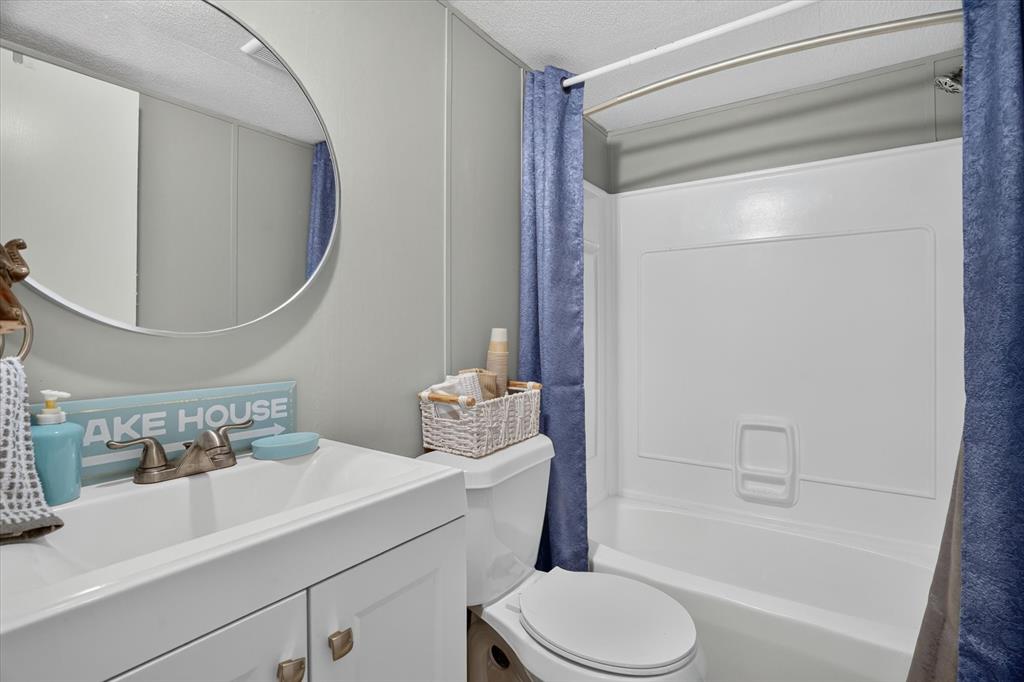 6602 Ashley Court Granbury, TX 76049 - Photo 11 of 35 Bathroom featuring a white vanity with integrated sink, brushed nickel faucet, and a circular wall mirror