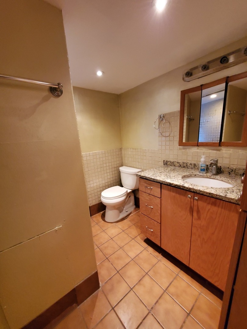 5135 West Roscoe Street, Unit B Chicago, IL 60641 - Photo 7 of 12 a bathroom with a sink a toilet and mirror
