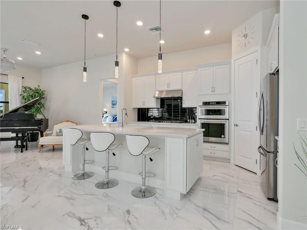 19724 Aqua View Lane Fort Myers, FL 33913 - Photo 13 of 44 a kitchen with white cabinets and stainless steel appliances