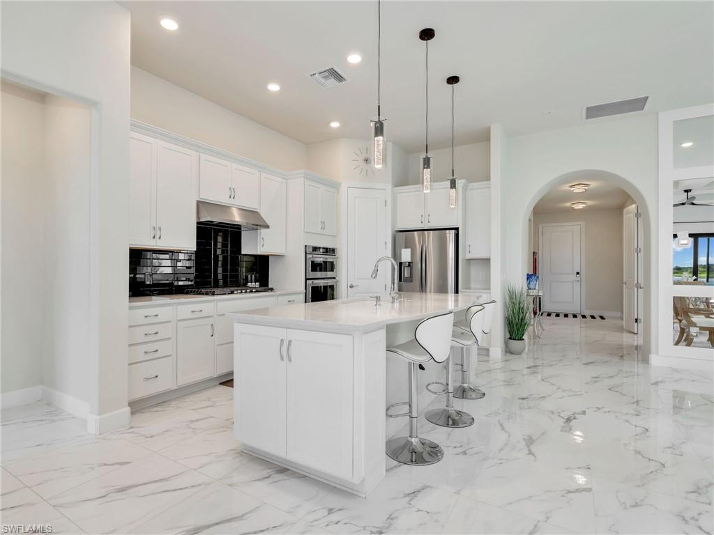 19724 Aqua View Lane Fort Myers, FL 33913 - Photo 14 of 44 a kitchen with white cabinets and stainless steel appliances