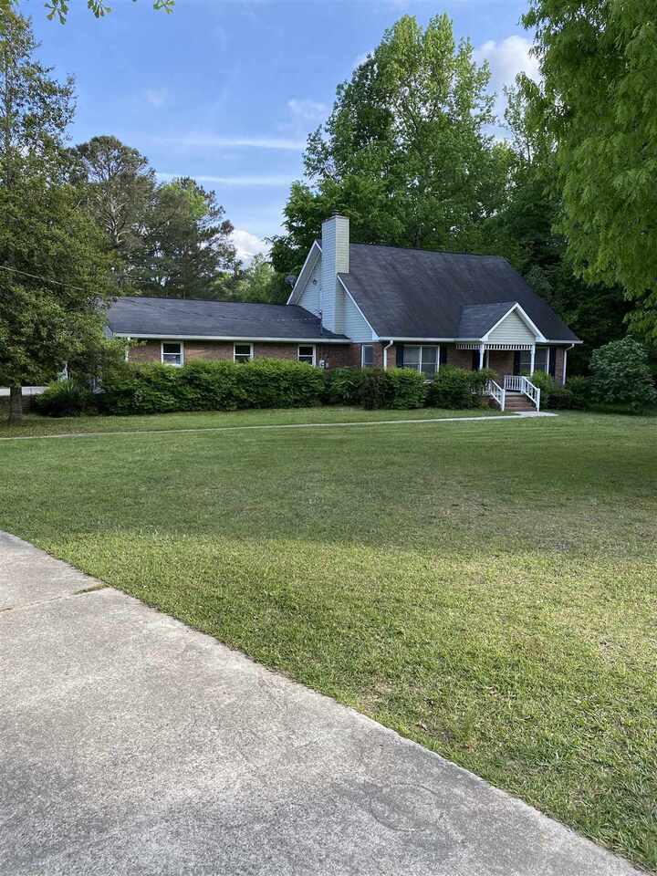 a view of a big house in a big yard with large trees