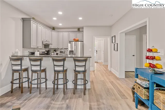 a kitchen with stainless steel appliances a dining table chairs stove and cabinets