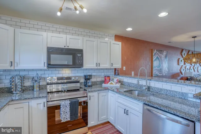 a kitchen with stainless steel appliances granite countertop a sink stove and microwave