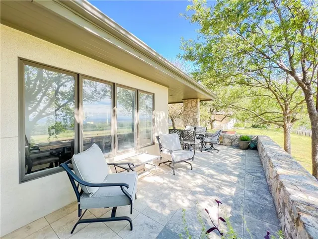 a view of a patio with table and chairs and floor to ceiling window and wooden fence