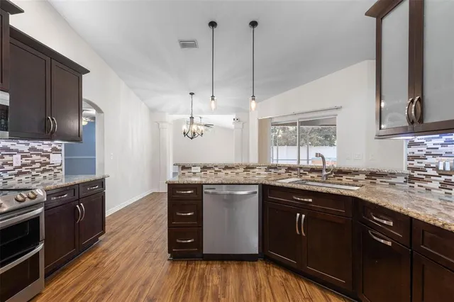 a kitchen with stainless steel appliances granite countertop wooden floors and sink