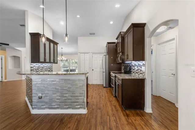 a kitchen with kitchen island granite countertop wooden floors and stainless steel appliances