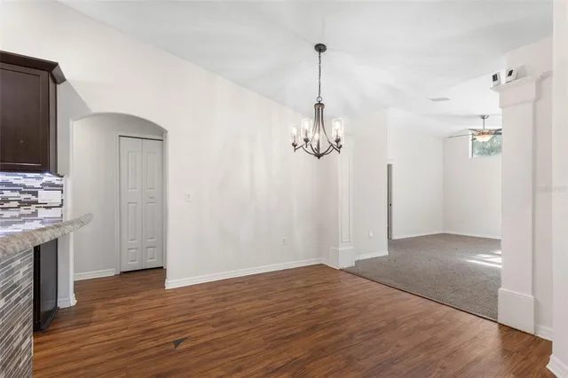 a view of empty room with wooden floor and kitchen view