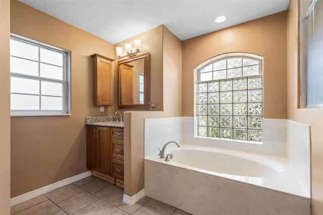 a bathroom with a granite countertop tub sink and mirror