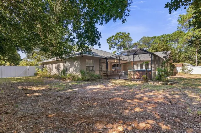 a backyard of a house with table and chairs under an umbrella