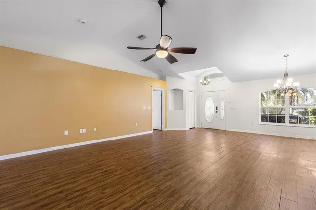 a view of an empty room with wooden floor and a ceiling fan
