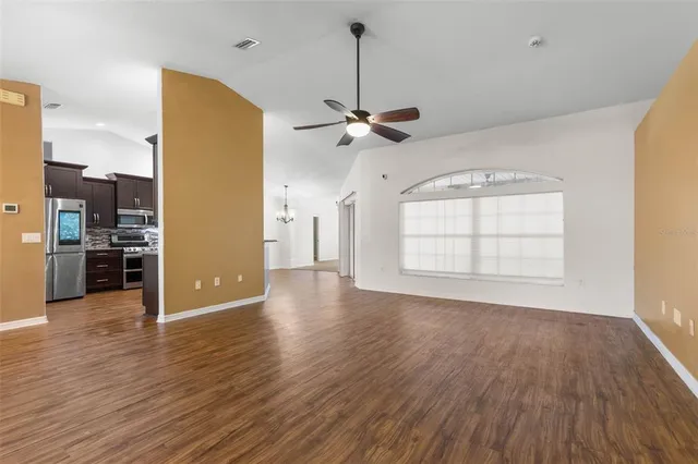 a view of a livingroom with wooden floor a ceiling fan and windows