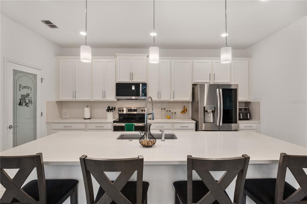 2887 Parkfield Road St. Cloud, FL 34772 - Photo 13 of 51 a kitchen with stainless steel appliances kitchen island granite countertop a dining table chairs refrigerator and microwave