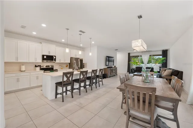 a dining room with stainless steel appliances kitchen island granite countertop a dining table chairs and view living room