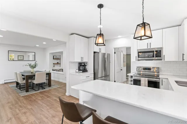 a kitchen with stainless steel appliances kitchen island a refrigerator a stove a sink a dining table and chairs