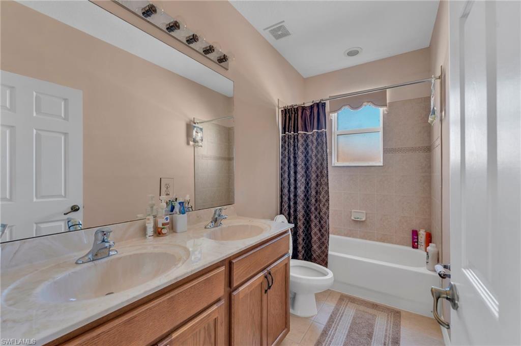 1966 Par Drive Naples, FL 34120 - Photo 15 of 32 Bathroom with double vanity, shower / bath combination with curtain, and light tile patterned flooring