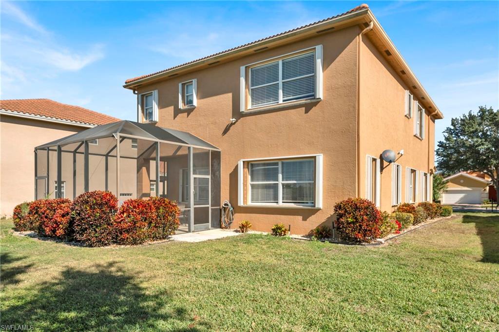 1966 Par Drive Naples, FL 34120 - Photo 20 of 32 Back of property with glass enclosure, stucco siding, a lawn, and a sunroom