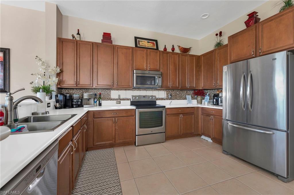 1966 Par Drive Naples, FL 34120 - Photo 4 of 32 Kitchen with appliances with stainless steel finishes, brown cabinets, light countertops, and light tile patterned floors