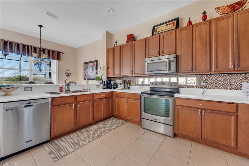 1966 Par Drive Naples, FL 34120 - Photo 5 of 32 Kitchen with brown cabinets, appliances with stainless steel finishes, a chandelier, and light countertops