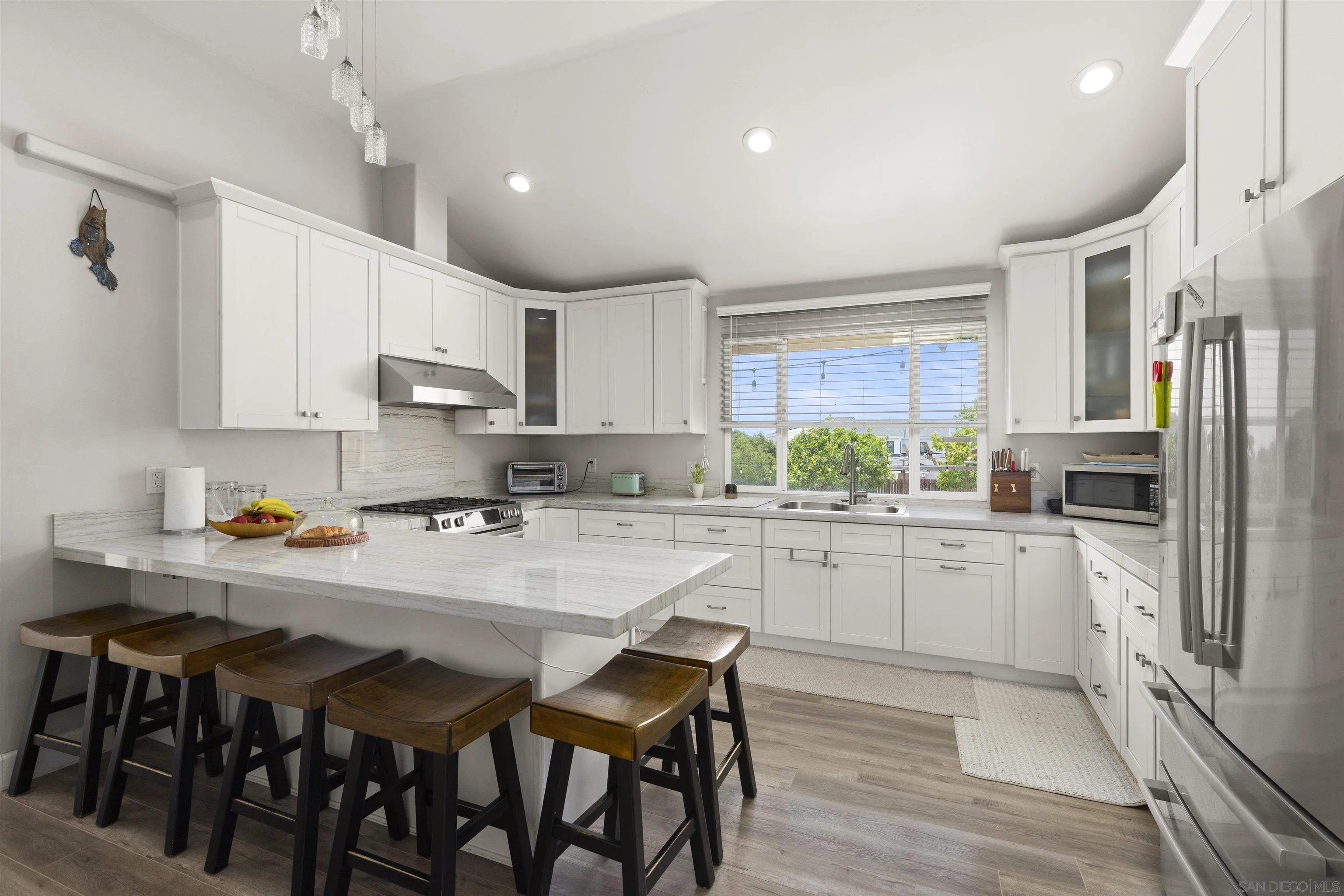 752 Bracero Road Encinitas, CA 92024 - Photo 15 of 46 a kitchen with stainless steel appliances granite countertop a table chairs sink refrigerator and cabinets