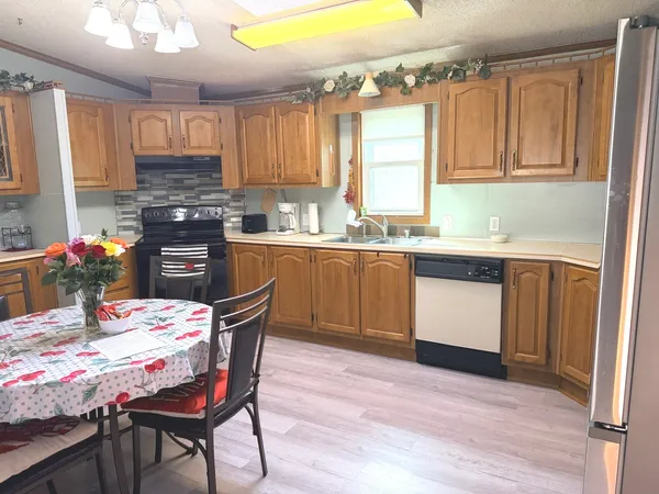 a kitchen with stainless steel appliances granite countertop wooden cabinets a stove top oven a sink and dishwasher with wooden floor