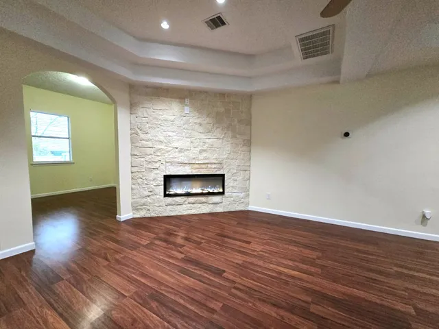 a view of an empty room with wooden floor fireplace and a window