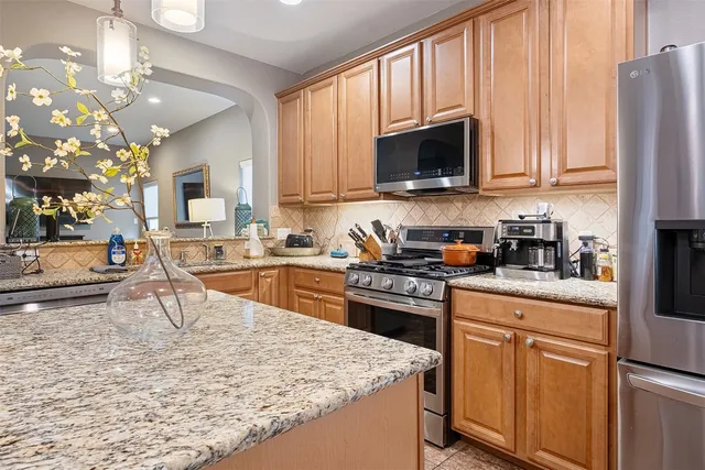 a kitchen with stainless steel appliances granite countertop a stove a sink dishwasher and a microwave oven with white cabinets