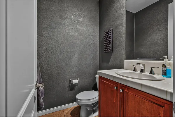 a bathroom with a granite countertop toilet sink and mirror