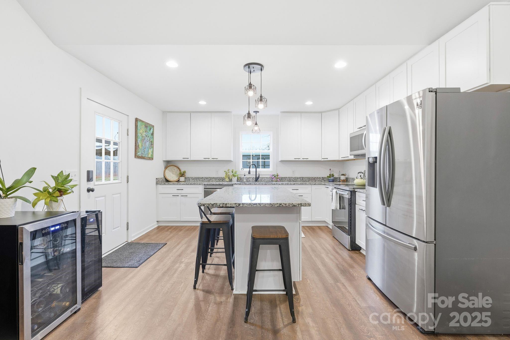 585 Stirewalt Road China Grove, NC 28023 - Photo 11 of 30 a kitchen with a refrigerator a sink dishwasher and white cabinets with wooden floor