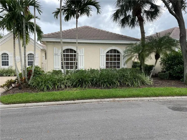 front view of a house with a yard and palm trees