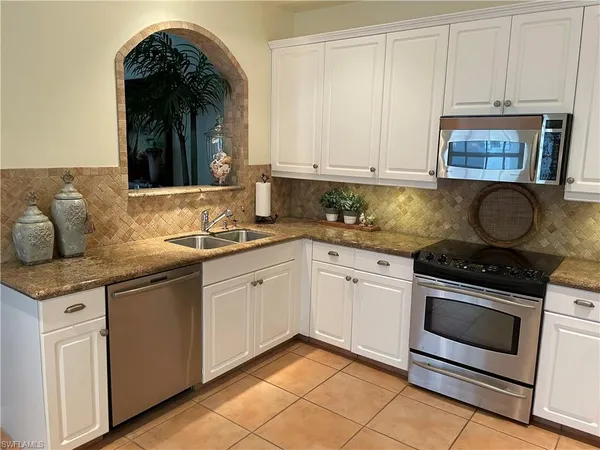 a kitchen with granite countertop white cabinets and white appliances
