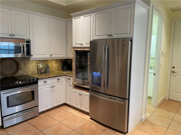 a kitchen with granite countertop a refrigerator stove and cabinets