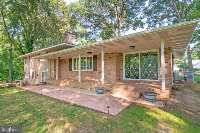 a backyard of a house with table and chairs and large tree