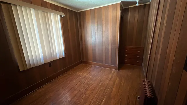 a view of empty room with wooden floor and a window