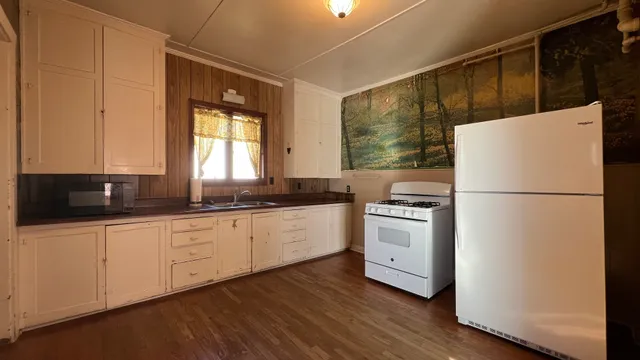 a kitchen with appliances cabinets a sink and a large window