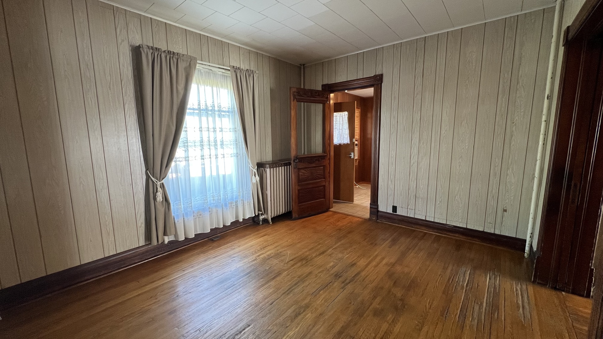 113 West Delaware Street Dwight, IL 60420 - Photo 7 of 21 an empty room with wooden floor and windows with curtains